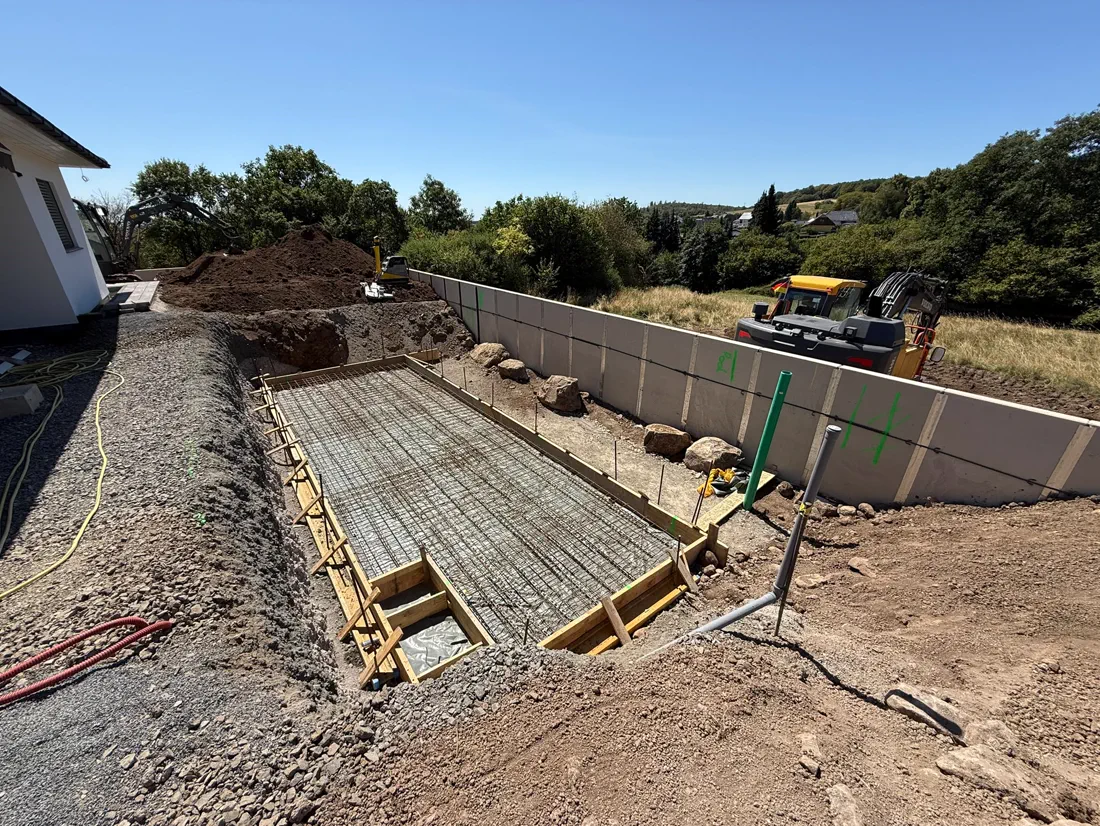 Bewehrte Betonschalung für eine Rampe zwischen zwei Stützwänden, Erdarbeiten ringsum