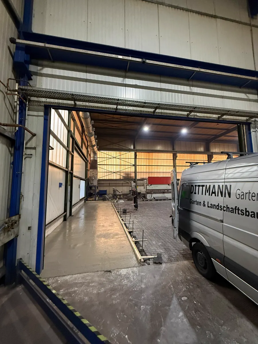 Innenaufnahme der Betriebshalle mit Transporter und gestapeltem Baumaterial