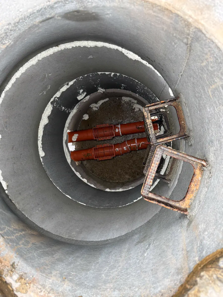 Draufsicht in einen Betonschachtring mit Zulaufrohr und Holzabstützung