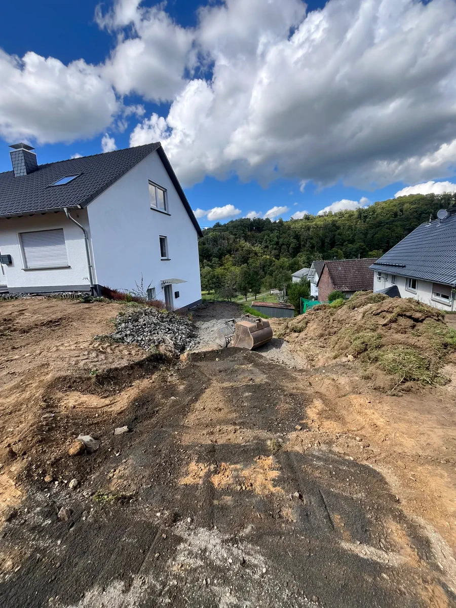 Großer Mutterbodenhügel vor einem Wohnhaus unter blauem Himmel