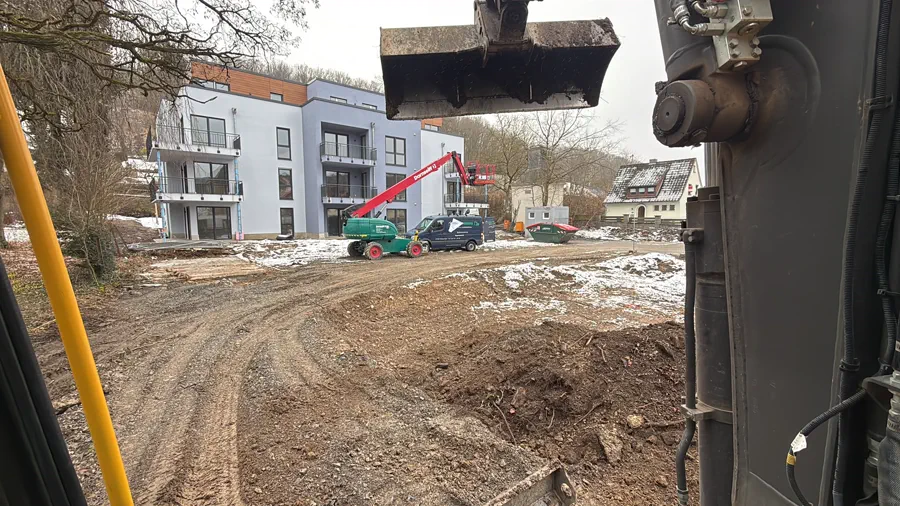 Blick über die Baggerschaufel auf eine aufgeweichte Baustellenzufahrt