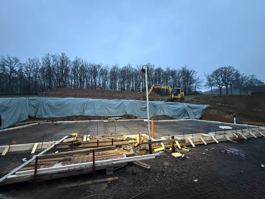 Hangbaustelle in der Dämmerung mit Schalung und Baumaterial