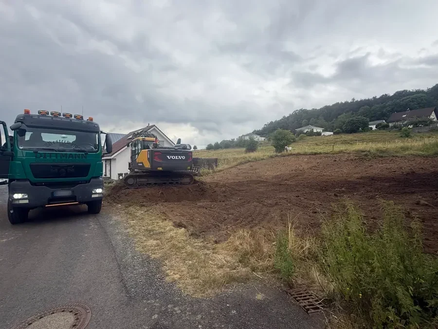 Kipper und Bagger des Betriebs auf der Straße vor dem abgeschobenen Gelände