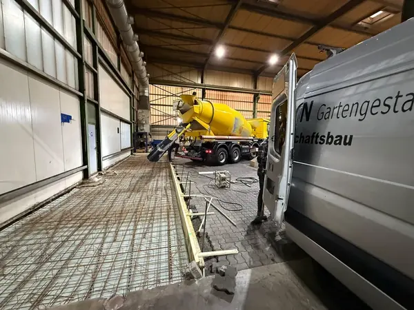 Fahrmischer betoniert die bewehrte Bodenplatte, rechts steht der Firmentransporter
