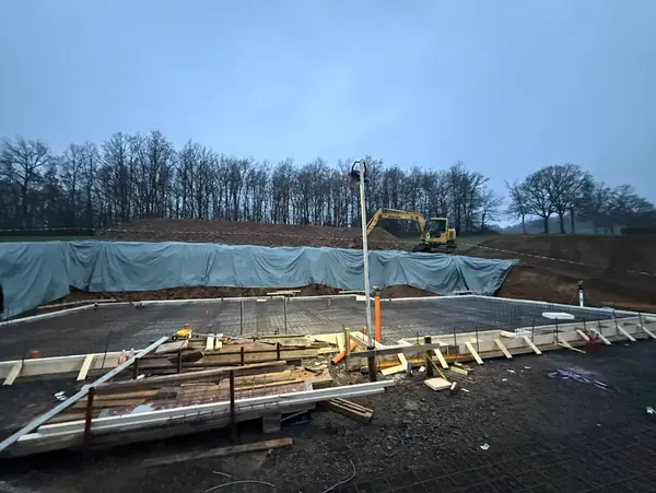 Hangbaustelle in der Dämmerung mit Schalung und Baumaterial