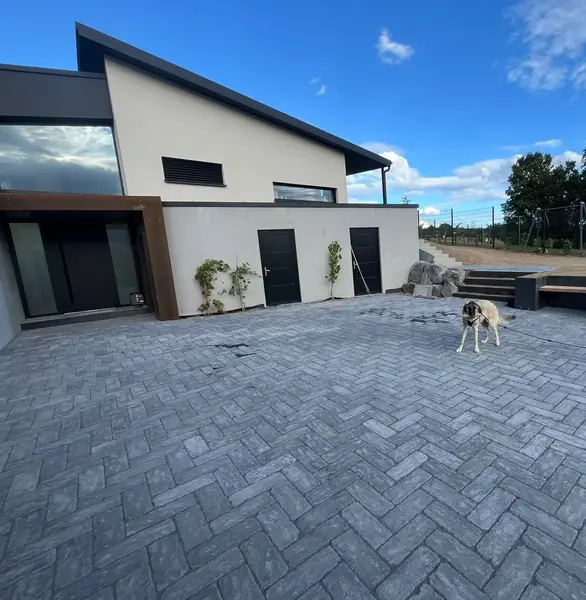 Große fertig gepflasterte Hoffläche im Fischgrätverband vor einem modernen Wohnhaus